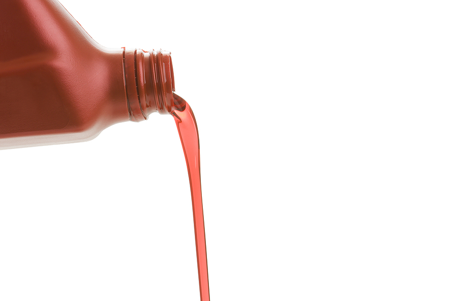 Transmission fluid pouring out of a bottle on a white background.