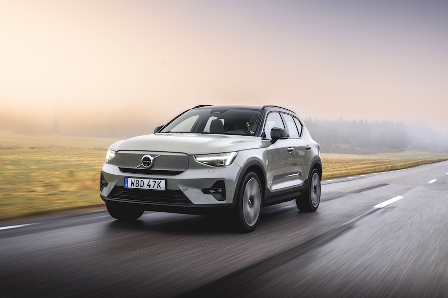 A Volvo XC40 Recharge is driving down the road in the countryside.